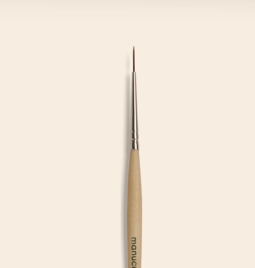 Paintbrush with a beige handle and silver ferrule on a beige background