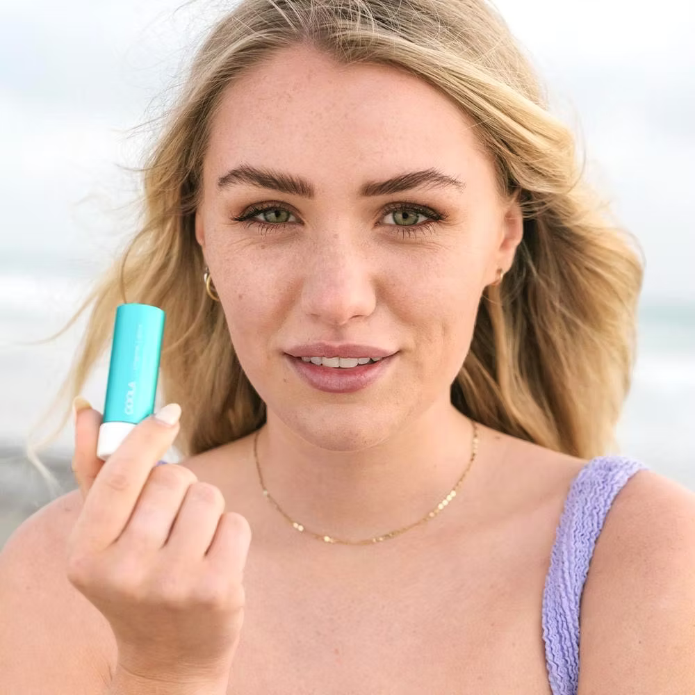 Woman holding a blue lip balm with a blurred background