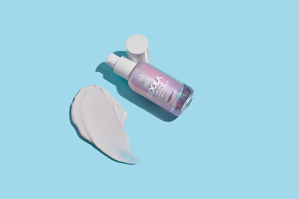 Skincare serum bottle with a swatch of cream on a light blue background