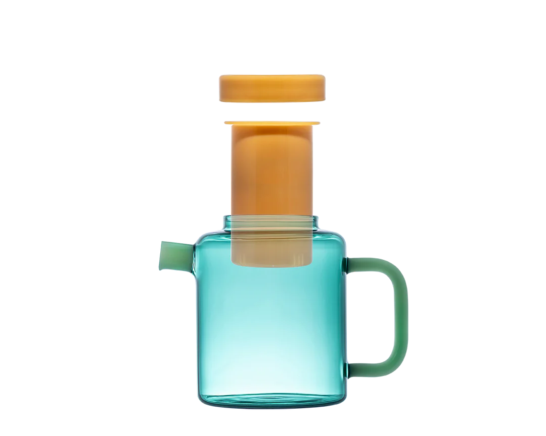 Clear blue glass pitcher with green handle and orange lid on a white background