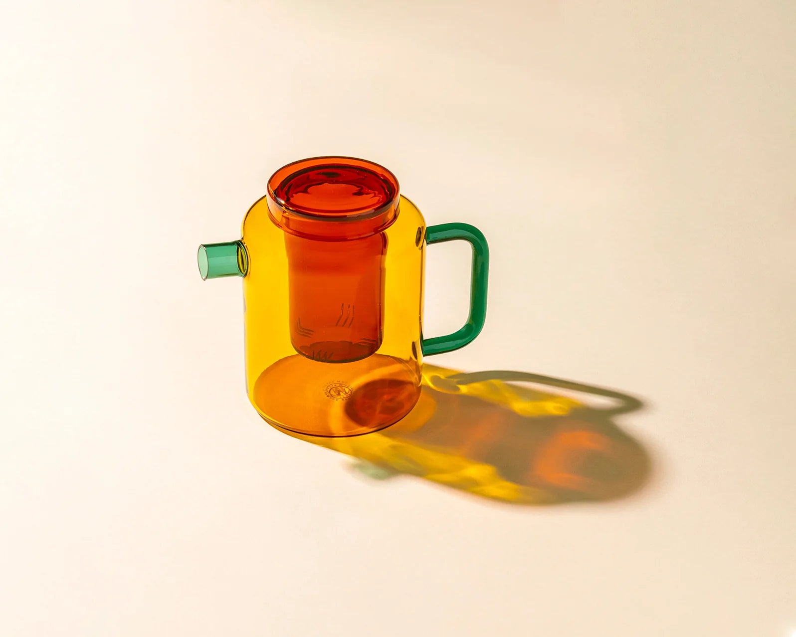 Multicolored glass container with a handle on a beige background