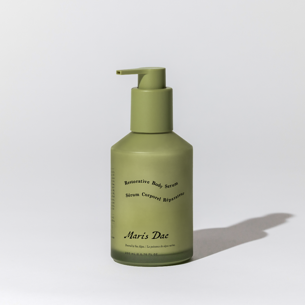 Green bottle with pump of 'Maris Dae' serum on a light gray background